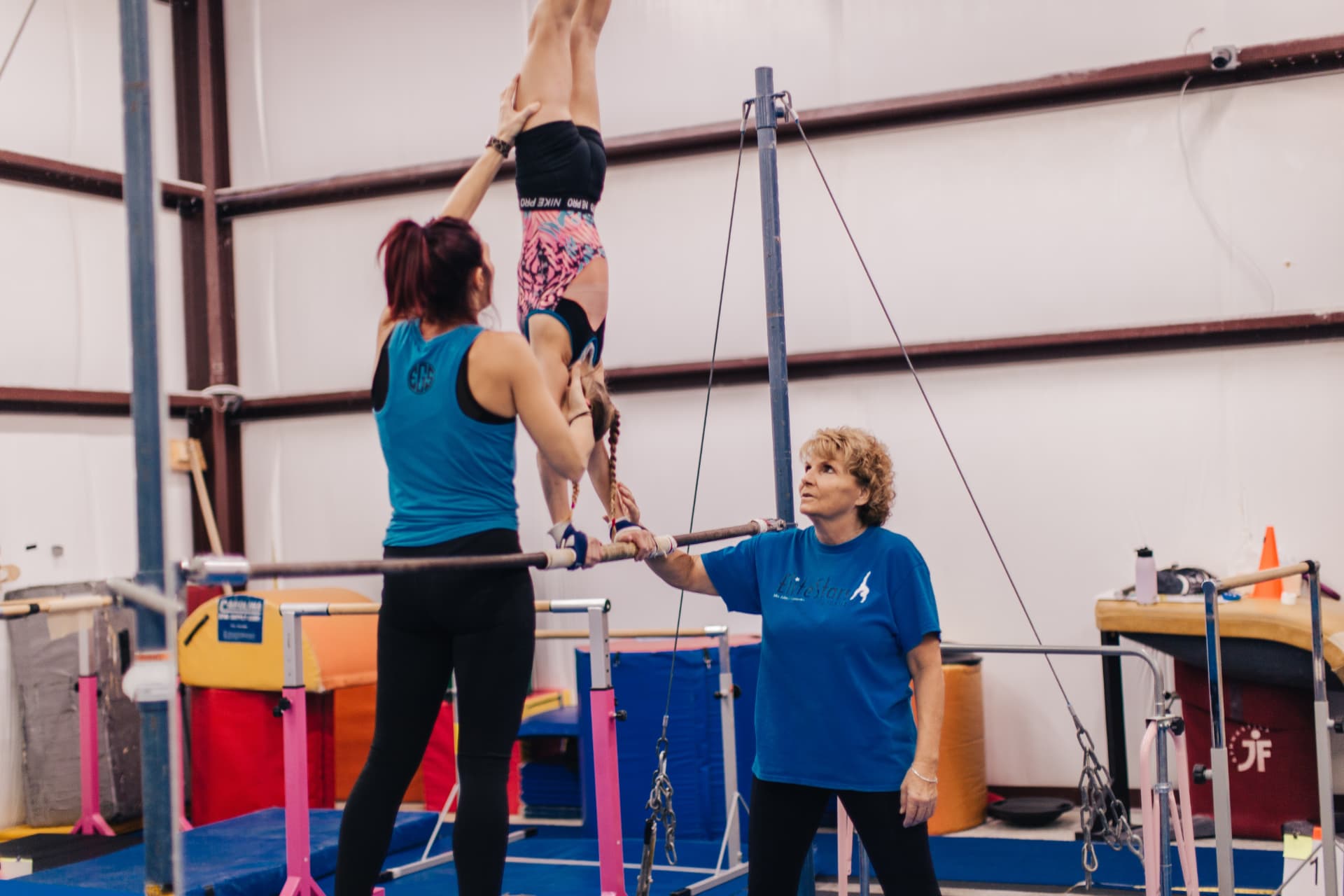 Coach spotting a gymnast on the bars at Miss Libby's